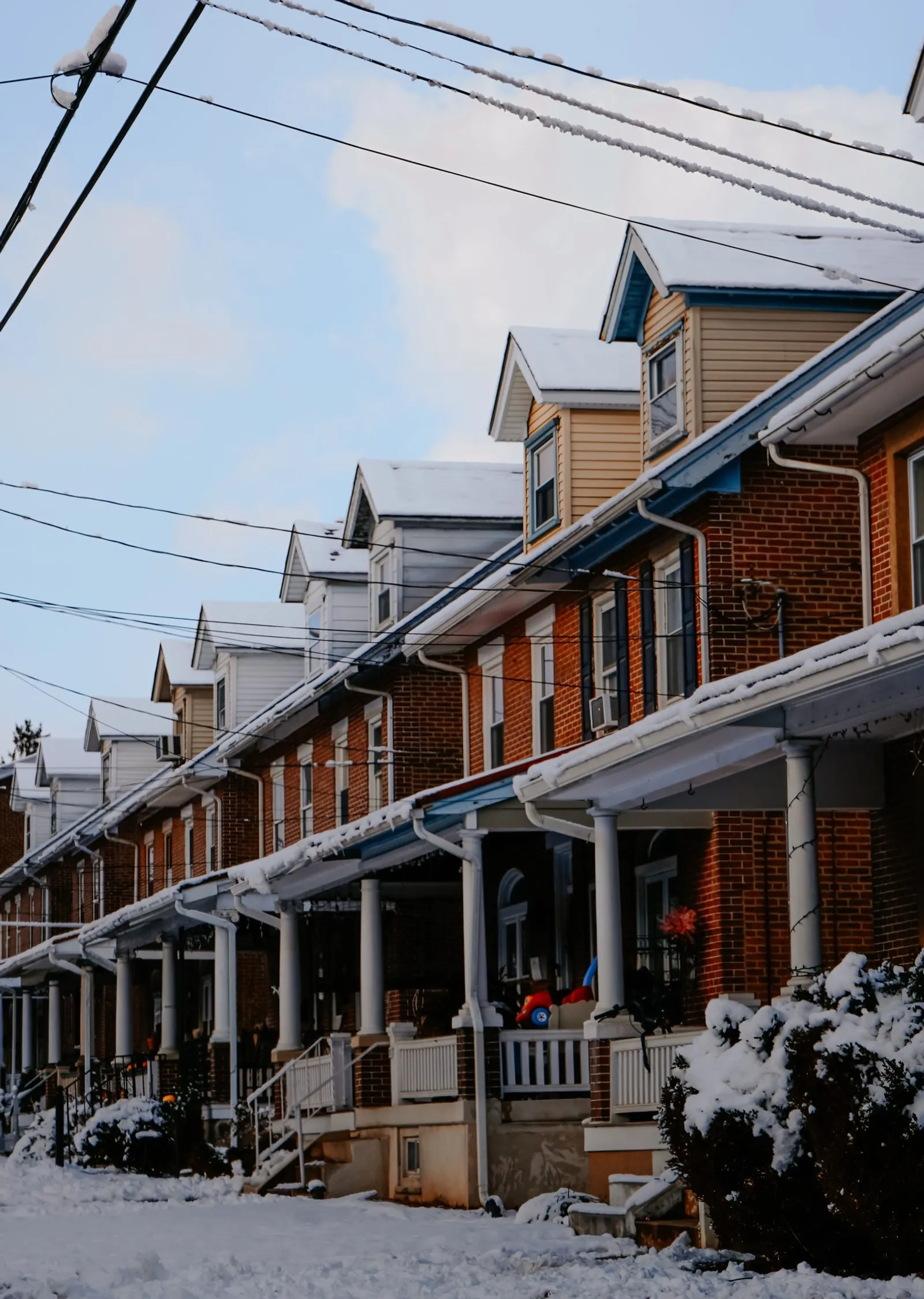 A row of NYC houses covered in snow, showing homes in every season